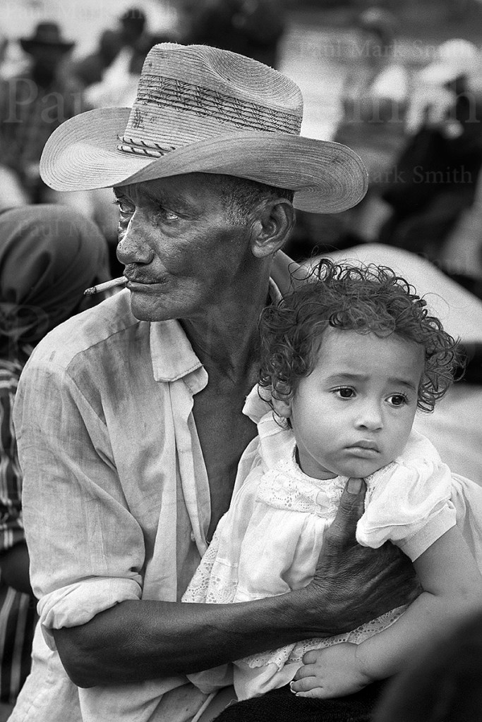 Farmer with cigarette holds a small girl