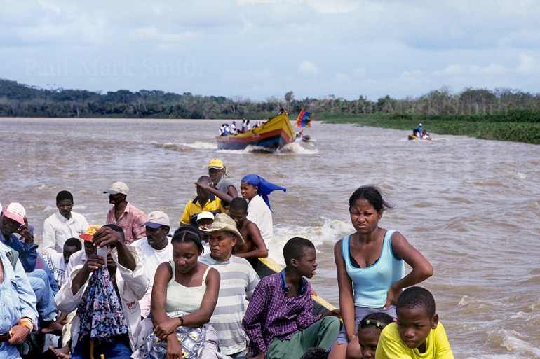 Displaced people in wooden boats that pass along a river