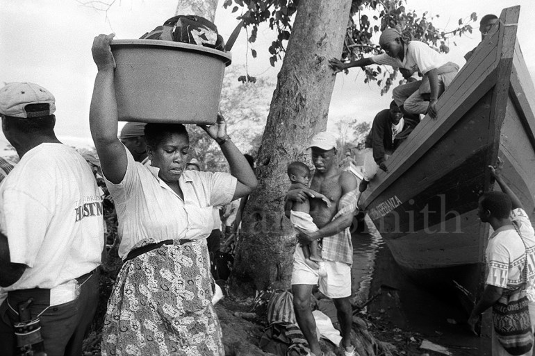 Passengers disembark from wooden boats carrying their luggage