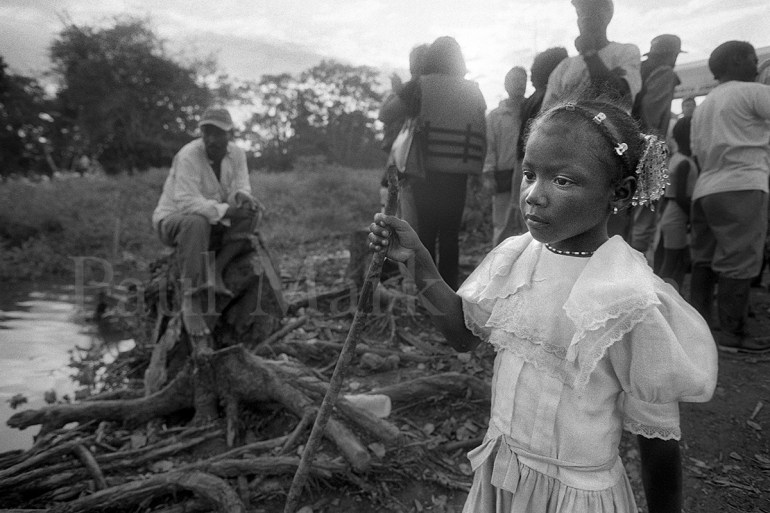 A young afro-colombian girl with a staff on the river's edge