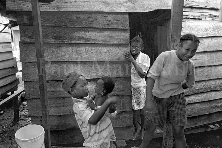 Displaced women and boy with girl baby in an area of wooden homes