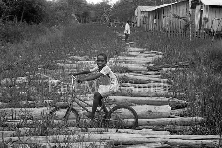 A boy on a bike surrounded by logs