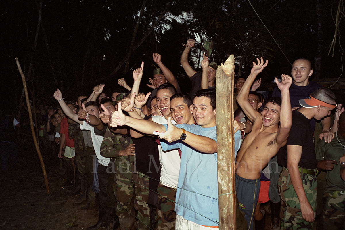 Captured, smiling and cheering soldiers and police behind a string fence