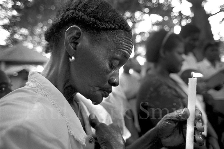 A widow with a candle in a Catholic mass to commemorate those killed in Operation Genesis