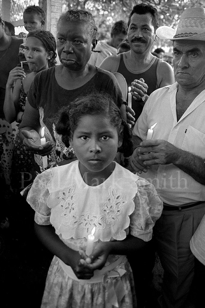 A young girl with a candle in a Catholic mass to commemorate those killed in Operation Genesis