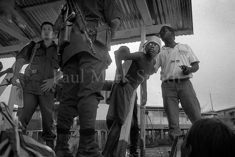 Police with rifles check documents whilst a boy looks at them
