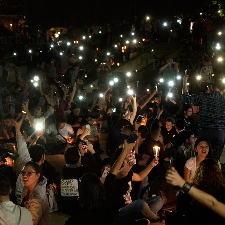 Youths hold cell phone torches aloft during vigil against police violence