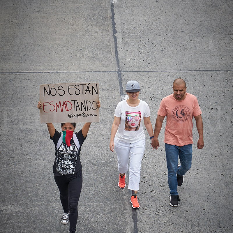 Woman with face covered with scarf carries placard. Couple walks hand in hand