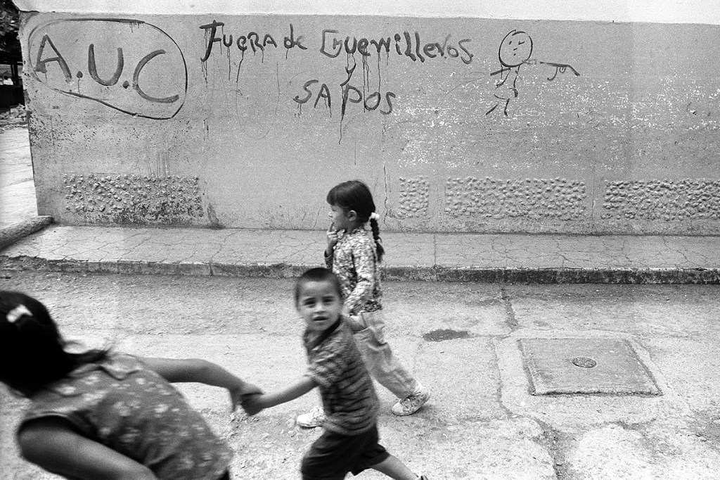 Children run by threatening graffiti painted by paramilitaries after a massacre