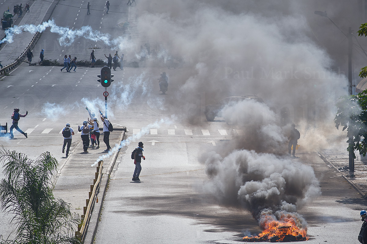 Burning barricade, protesters and tear gas cannisters flying in