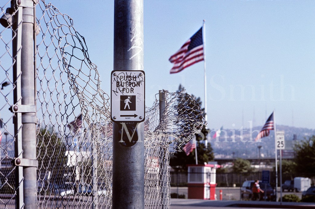 Bent down chain-link fencing and USA flags
